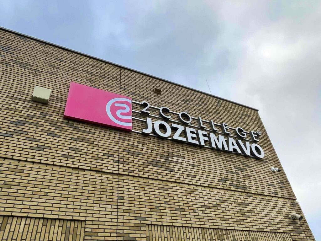 Lichtreclame van 2College Jozefmavo op een bakstenen gevel