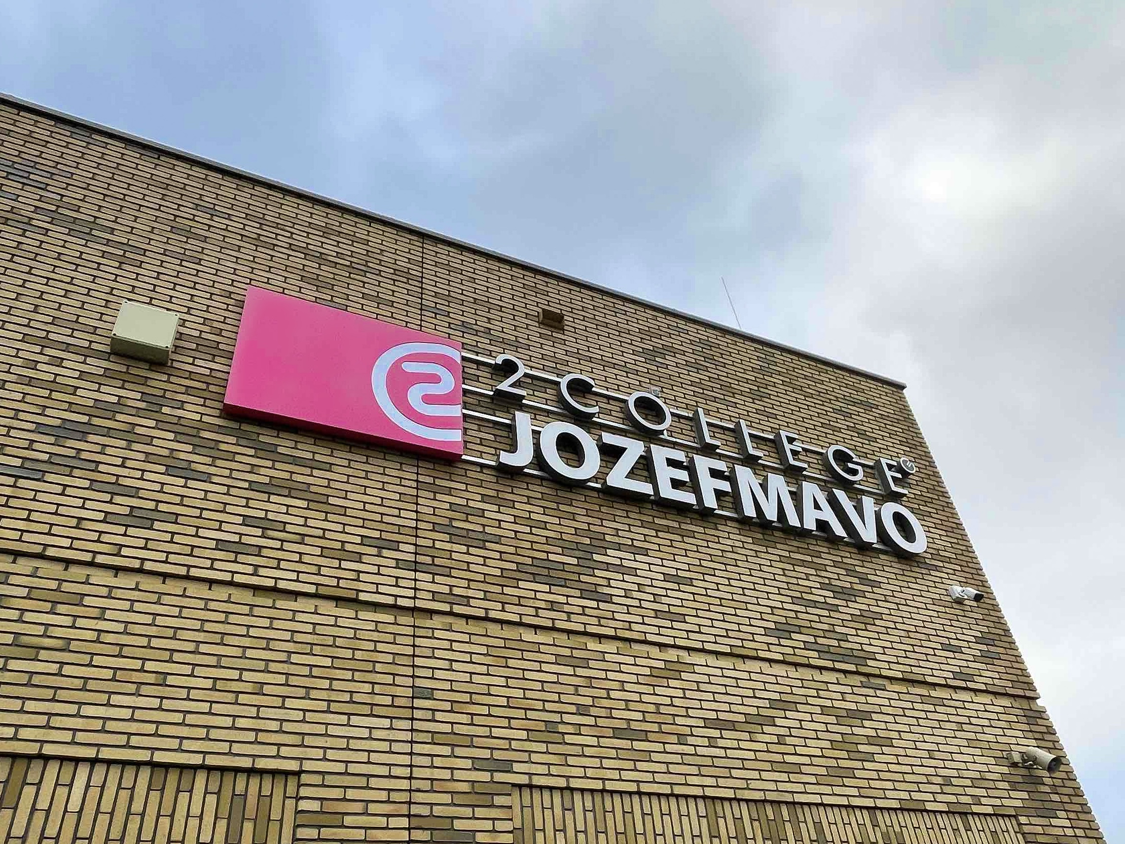 Lichtreclame van 2College Jozefmavo op een bakstenen gevel