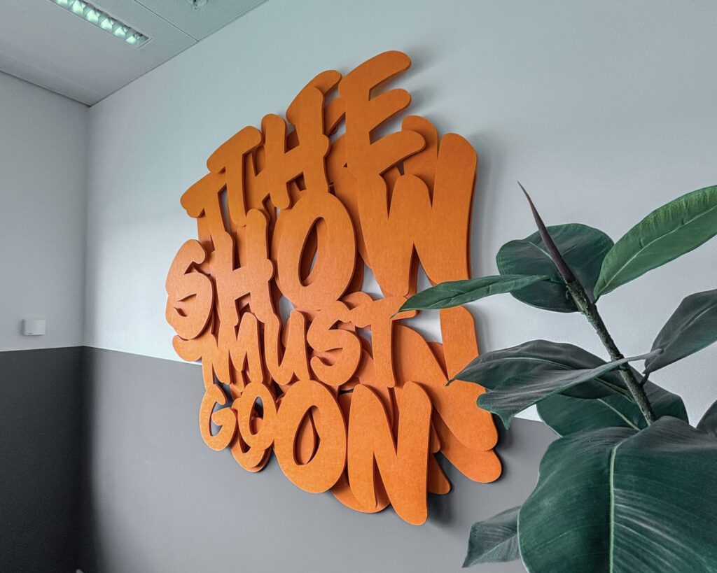 Oranje freesletters op een muur van Aces Direct
