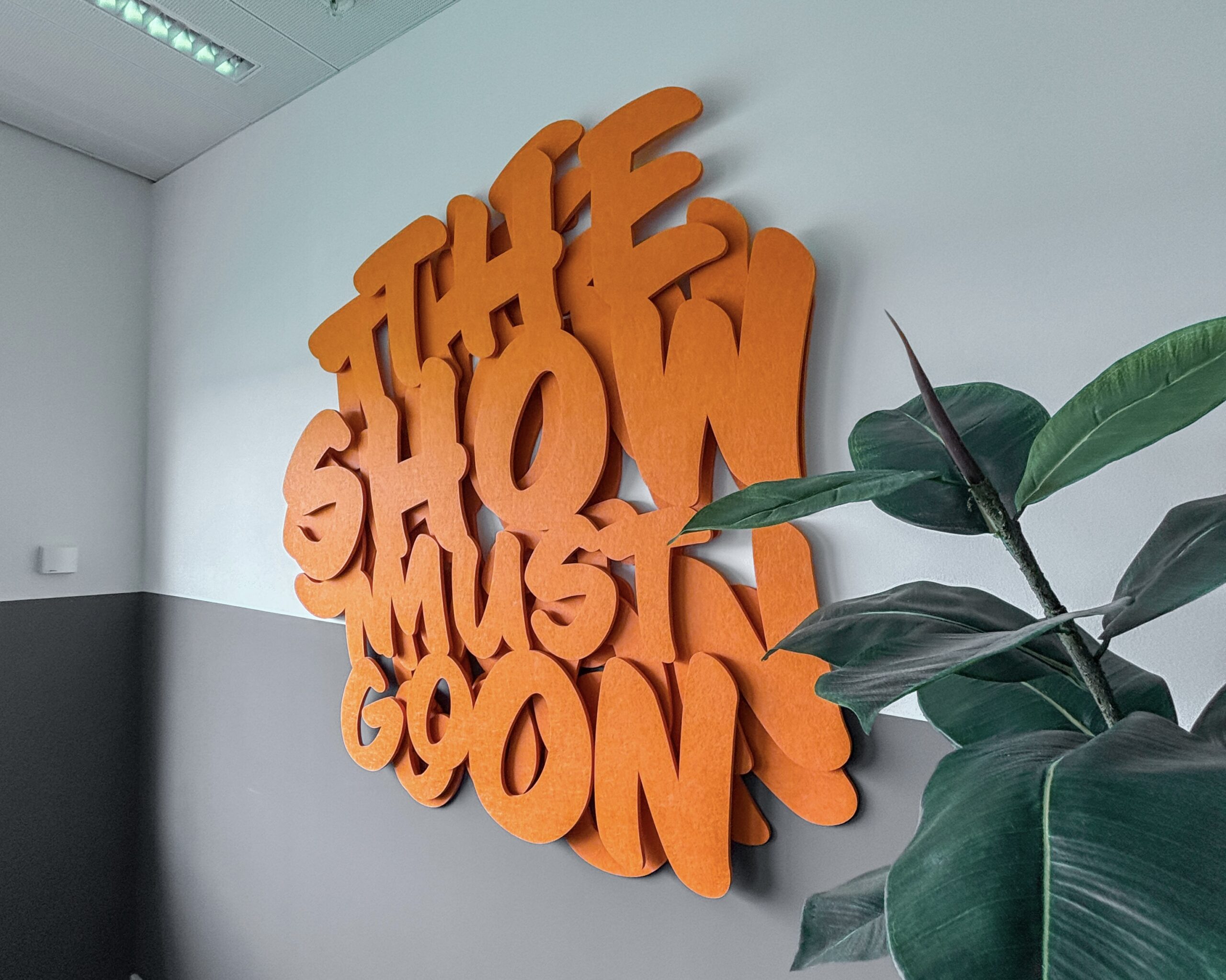 Oranje freesletters op een muur van Aces Direct